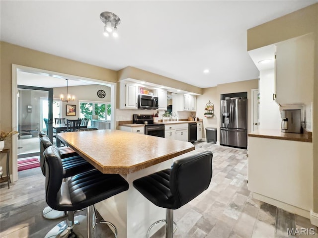 1171 Thunder Mountain Rd, Camdenton, MO 65020 - kitchen featuring appliances with stainless steel finishes, a kitchen bar, white cabinets, a chandelier, and light countertops