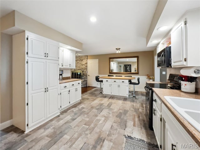 1171 Thunder Mountain Rd, Camdenton, MO 65020 - kitchen with black range with electric stovetop, light countertops, white cabinets, recessed lighting, and a kitchen island
