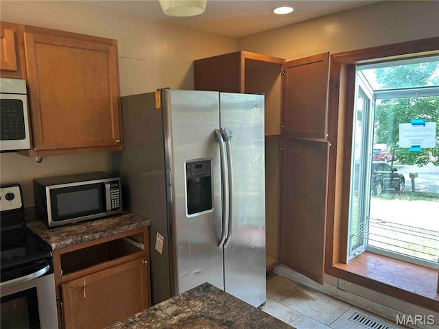 12922 High Crest St, Black Jack, MO 63033 - kitchen featuring stainless steel appliances, dark stone counters, light tile patterned floors, brown cabinetry, and recessed lighting