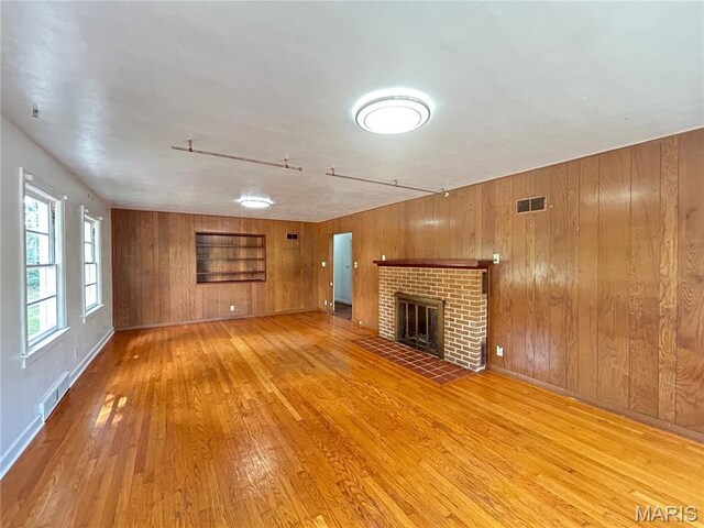 1203 N Main St, Salem, MO 65560 - unfurnished living room with light wood-style floors, wooden walls, and a brick fireplace