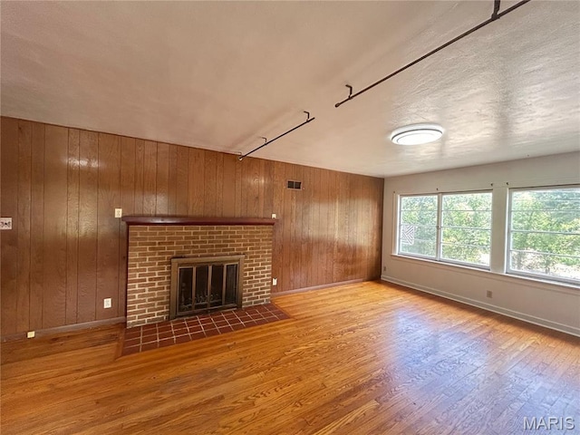 1203 N Main St, Salem, MO 65560 - unfurnished living room featuring wood walls, wood finished floors, and a fireplace