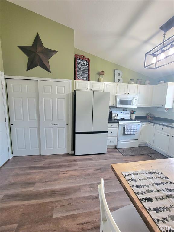 346 Cartpath Ln, Saint Clair, MO 63077 - kitchen with white appliances, lofted ceiling, white cabinetry, dark countertops, and wood finished floors