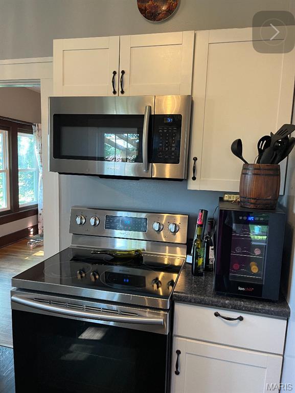 110 Brand Pl, Bonne Terre, MO 63628 - kitchen with appliances with stainless steel finishes, white cabinets, wood finished floors, and dark stone counters