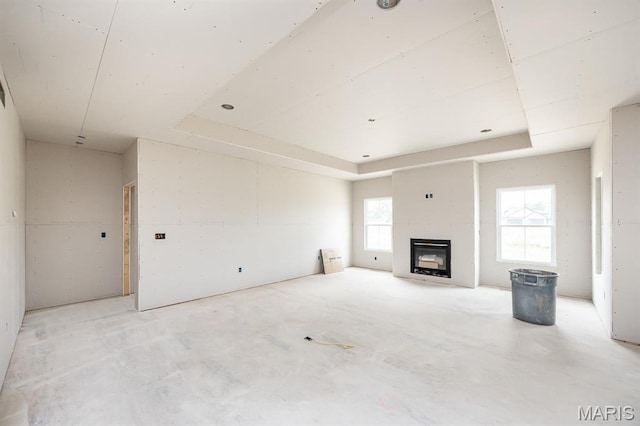 505 Master Ct, Shiloh, IL 62221 - unfurnished living room featuring a tray ceiling, concrete flooring, and plenty of natural light