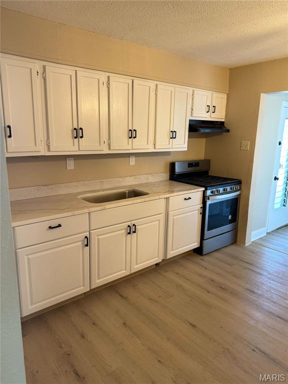 720 Southwell Ln, Florissant, MO 63031 - kitchen featuring stainless steel gas range, under cabinet range hood, white cabinetry, and a textured ceiling