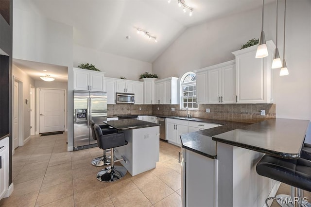 437 Marbleton Cir, Ofallon, IL 62269 - kitchen featuring stainless steel appliances, track lighting, a breakfast bar area, dark countertops, and high vaulted ceiling
