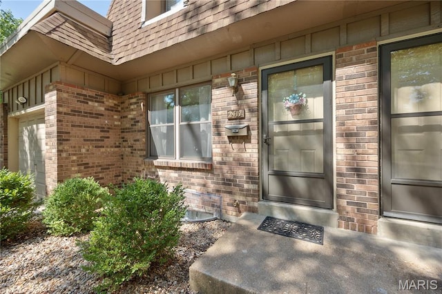 2417 Charente Dr, Maryland Heights, MO 63043 - doorway to property featuring brick siding, board and batten siding, and a shingled roof