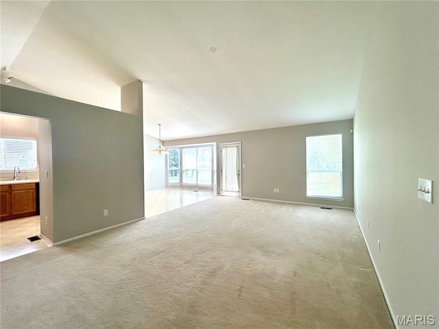 2401 Mountain Range Ct, Pacific, MO 63069 - unfurnished living room featuring light carpet, healthy amount of natural light, a chandelier, and lofted ceiling