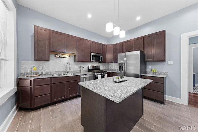 3615 Nebraska Ave, Saint Louis, MO 63118 - kitchen with stainless steel appliances, backsplash, hanging light fixtures, light wood-type flooring, and a kitchen island