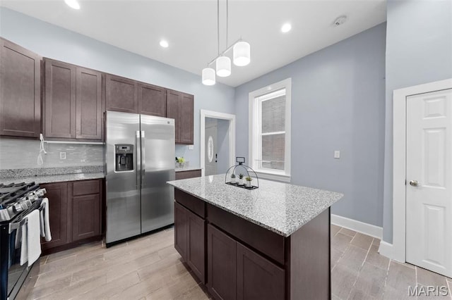 3615 Nebraska Ave, Saint Louis, MO 63118 - kitchen featuring appliances with stainless steel finishes, light stone countertops, a kitchen island, pendant lighting, and dark brown cabinets