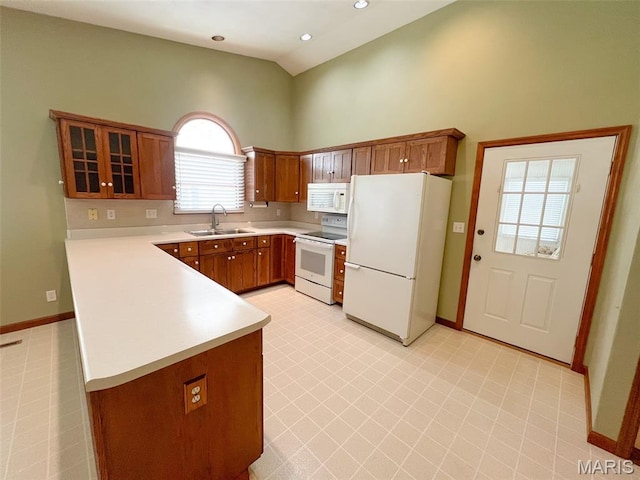 138 S 33rd St, Belleville, IL 62226 - kitchen featuring white appliances, a peninsula, brown cabinetry, light countertops, and high vaulted ceiling