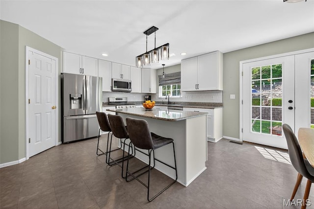 2426 Guardian Ct, Arnold, MO 63010 - kitchen featuring stainless steel appliances, a kitchen breakfast bar, tasteful backsplash, hanging light fixtures, and white cabinetry