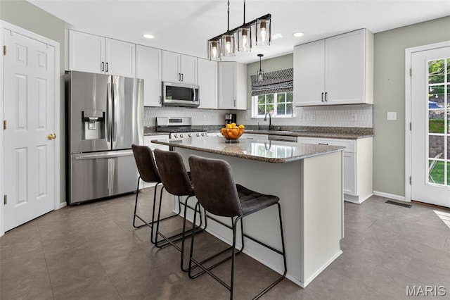 2426 Guardian Ct, Arnold, MO 63010 - kitchen featuring appliances with stainless steel finishes, backsplash, a breakfast bar area, a kitchen island, and pendant lighting