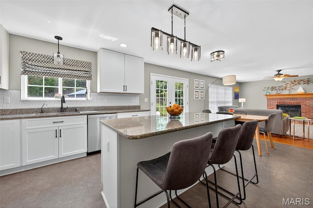 2426 Guardian Ct, Arnold, MO 63010 - kitchen featuring stainless steel dishwasher, a kitchen bar, a fireplace, and tasteful backsplash