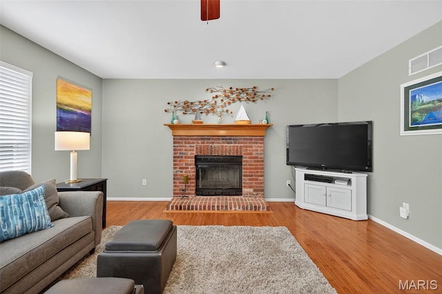 2426 Guardian Ct, Arnold, MO 63010 - living room featuring wood finished floors, a brick fireplace, and a ceiling fan