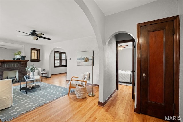 4932 Fairview Ave, Saint Louis, MO 63139 - living room featuring a ceiling fan, arched walkways, light wood finished floors, and a brick fireplace