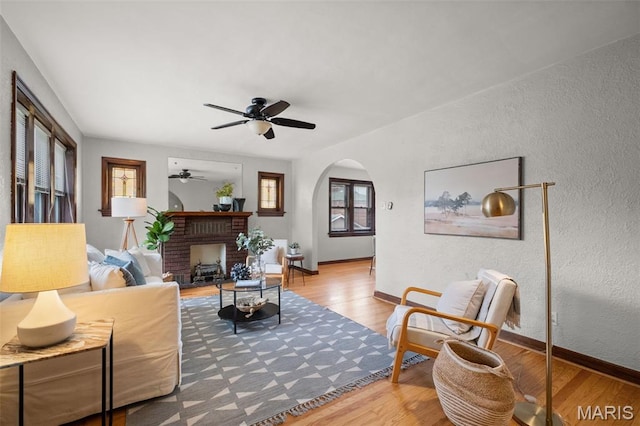 4932 Fairview Ave, Saint Louis, MO 63139 - living area featuring wood finished floors, ceiling fan, arched walkways, a textured wall, and a brick fireplace