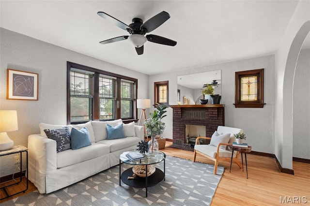 4932 Fairview Ave, Saint Louis, MO 63139 - living area with a textured wall, wood finished floors, a ceiling fan, a brick fireplace, and arched walkways