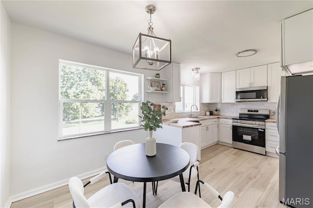 7315 Cheshire Ln, Affton, MO 63123 - kitchen featuring appliances with stainless steel finishes, decorative backsplash, a chandelier, light countertops, and light wood-style floors