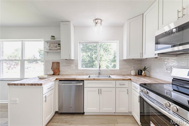 7315 Cheshire Ln, Affton, MO 63123 - kitchen with appliances with stainless steel finishes, open shelves, healthy amount of natural light, and a peninsula