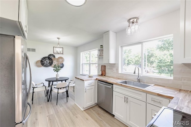 7315 Cheshire Ln, Affton, MO 63123 - kitchen featuring stainless steel appliances, light wood finished floors, white cabinets, and decorative backsplash