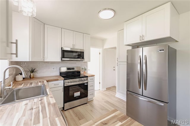 7315 Cheshire Ln, Affton, MO 63123 - kitchen with appliances with stainless steel finishes, wood counters, white cabinets, decorative backsplash, and light wood-style floors