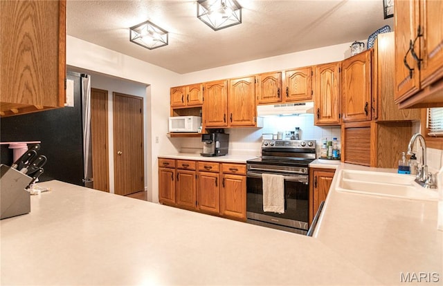 921 Mallard Sq, Rolla, MO 65401 - kitchen with stainless steel appliances, under cabinet range hood, light countertops, decorative backsplash, and brown cabinetry