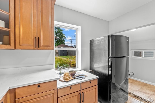 2725 Macklind Ave, Saint Louis, MO 63139 - kitchen featuring freestanding refrigerator, light countertops, glass insert cabinets, and light tile patterned flooring