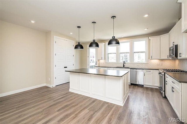 1347 W Gateway Hts W Unit 53-603, Richmond Heights, MO 63144 - kitchen with stainless steel appliances, dark countertops, a kitchen island, tasteful backsplash, and light wood finished floors