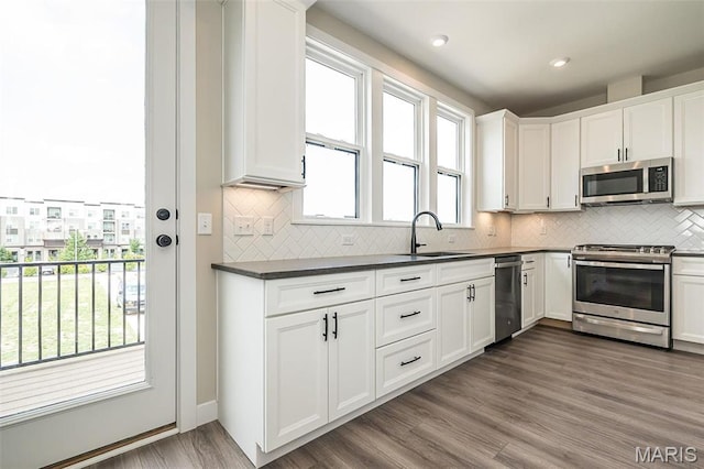 1347 W Gateway Hts W Unit 53-603, Richmond Heights, MO 63144 - kitchen with stainless steel appliances, dark countertops, white cabinets, decorative backsplash, and wood finished floors