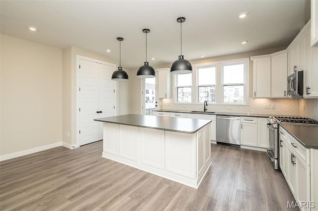 1347 W Gateway Hts W Unit 53-603, Richmond Heights, MO 63144 - kitchen with stainless steel appliances, dark countertops, a kitchen island, backsplash, and light wood-type flooring