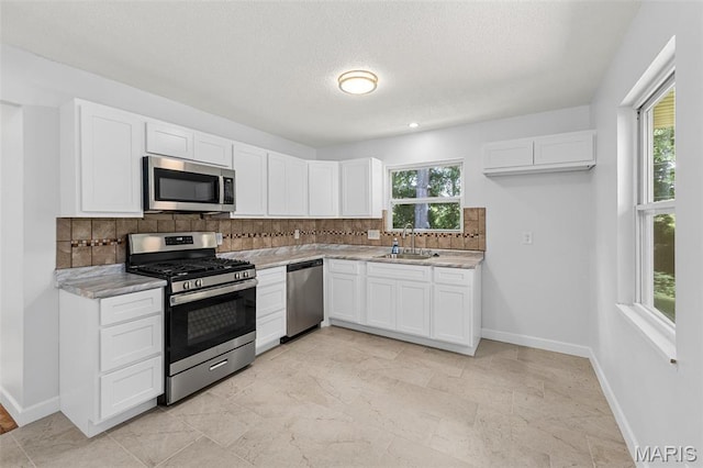 2315 Bramble Ln, Florissant, MO 63033 - kitchen with appliances with stainless steel finishes, decorative backsplash, white cabinets, and a textured ceiling