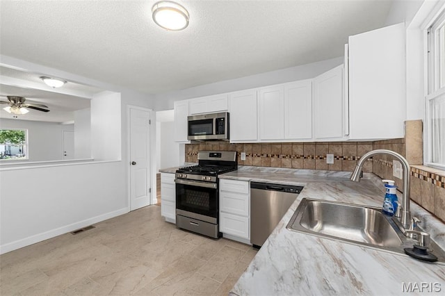 2315 Bramble Ln, Florissant, MO 63033 - kitchen with stainless steel appliances, white cabinetry, backsplash, a ceiling fan, and a textured ceiling