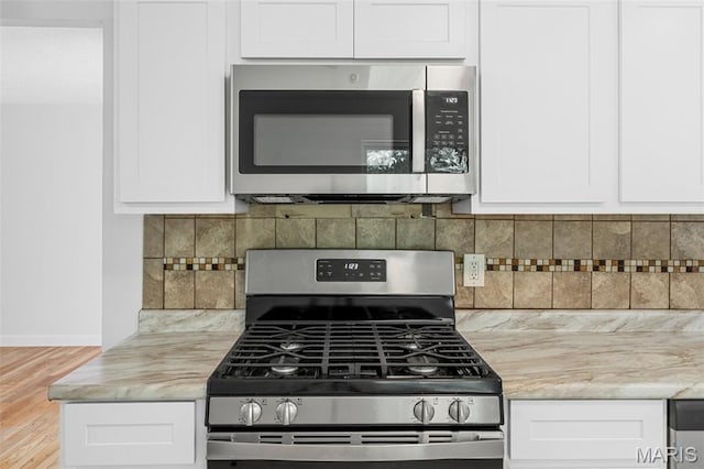 2315 Bramble Ln, Florissant, MO 63033 - kitchen with stainless steel appliances, white cabinets, and backsplash
