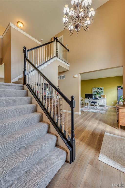 3026 Windsor Point Dr, Saint Louis, MO 63129 - stairway featuring a chandelier, wood finished floors, and a towering ceiling