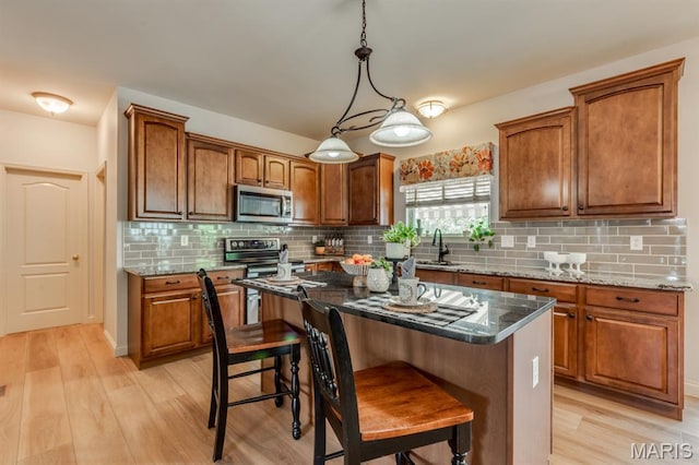3026 Windsor Point Dr, Saint Louis, MO 63129 - kitchen featuring appliances with stainless steel finishes, light wood-style floors, brown cabinetry, and a breakfast bar