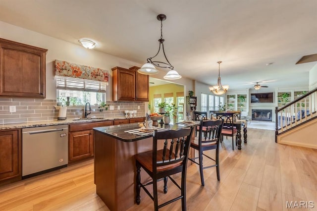 3026 Windsor Point Dr, Saint Louis, MO 63129 - kitchen with dishwasher, a kitchen bar, tasteful backsplash, brown cabinetry, and a glass covered fireplace