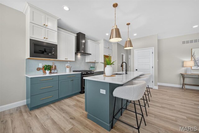 554 Wheatfield Cir, Ofallon, MO 63385 - kitchen with wall chimney range hood, gas range, black microwave, backsplash, and light wood-style flooring