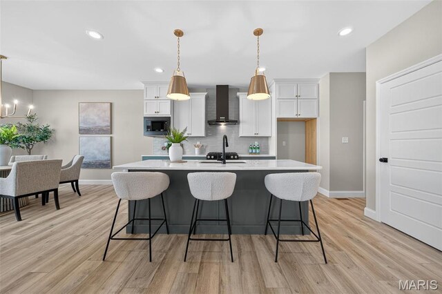 554 Wheatfield Cir, Ofallon, MO 63385 - kitchen with wall chimney exhaust hood, built in microwave, light countertops, tasteful backsplash, and a kitchen island with sink