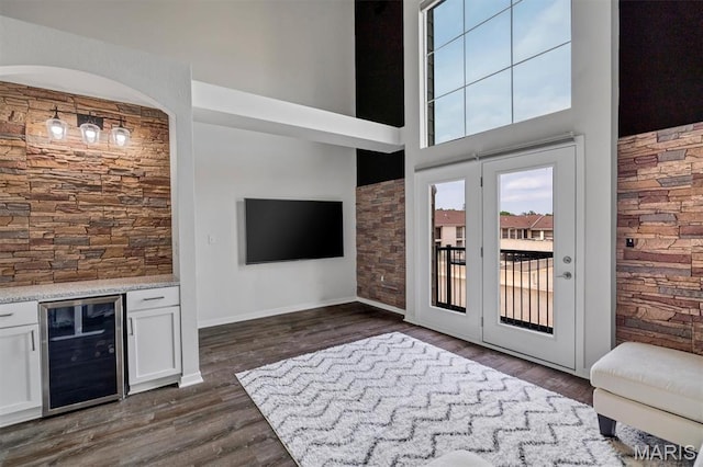 200 S Kirkwood Rd Unit 317, Kirkwood, MO 63122 - unfurnished living room featuring beverage cooler, dark wood-style floors, a towering ceiling, and a bar