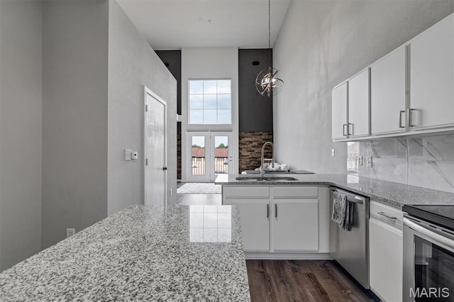 200 S Kirkwood Rd Unit 317, Kirkwood, MO 63122 - kitchen featuring appliances with stainless steel finishes, white cabinets, light stone countertops, dark wood-style flooring, and backsplash