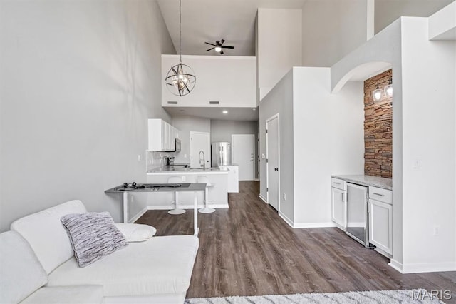 200 S Kirkwood Rd Unit 317, Kirkwood, MO 63122 - living room with a high ceiling, a chandelier, dark wood-style flooring, arched walkways, and ceiling fan
