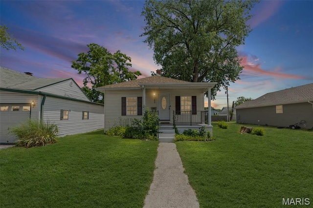 208 Washington Ave, East Alton, IL 62024 - bungalow-style house featuring covered porch, a yard, and a garage