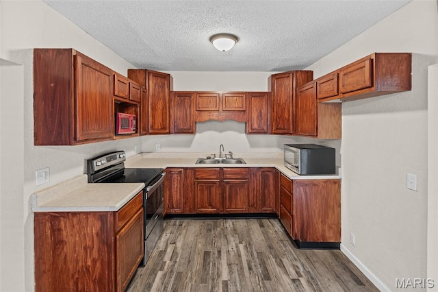 208 Washington Ave, East Alton, IL 62024 - kitchen with appliances with stainless steel finishes, wood finished floors, a textured ceiling, light countertops, and brown cabinets