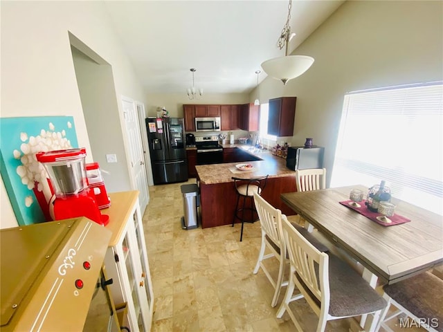 145 Champions Ln, Wentzville, MO 63385 - kitchen featuring stainless steel appliances, a peninsula, high vaulted ceiling, light countertops, and a chandelier