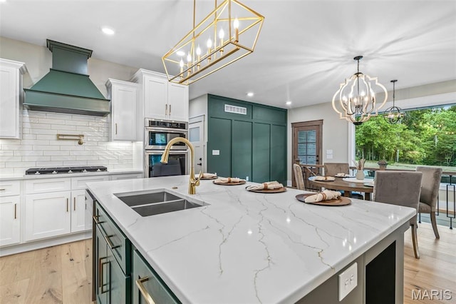 10028 Debbie Pl, Bonne Terre, MO 63628 - kitchen with premium range hood, stovetop, a chandelier, stainless steel double oven, and light wood finished floors