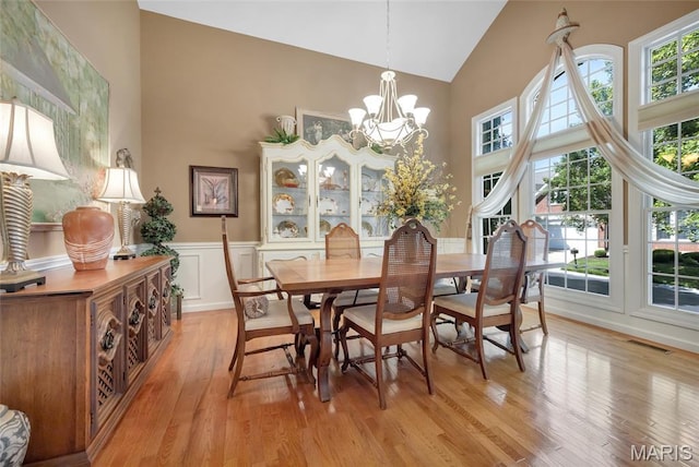 112 Wake Forest Pl, Ofallon, MO 63368 - dining space with high vaulted ceiling, light wood-style floors, a chandelier, and a wainscoted wall