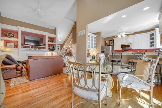 112 Wake Forest Pl, Ofallon, MO 63368 - dining area featuring a ceiling fan, light wood-type flooring, a fireplace, recessed lighting, and high vaulted ceiling
