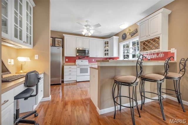 112 Wake Forest Pl, Ofallon, MO 63368 - kitchen with appliances with stainless steel finishes, a breakfast bar, light wood-type flooring, a peninsula, and white cabinetry