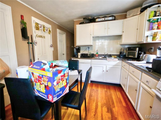 5912 Arsenal St, Saint Louis, MO 63139 - kitchen with white cabinets, crown molding, decorative backsplash, light wood finished floors, and white dishwasher